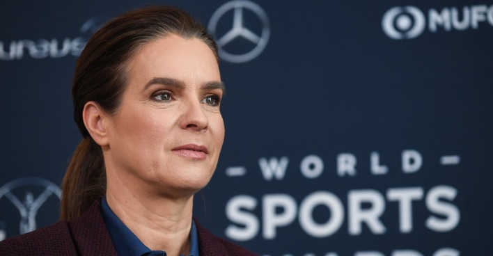 Katharina Witt vor einer Fotoleinwand mit geschlossenen Haaren.