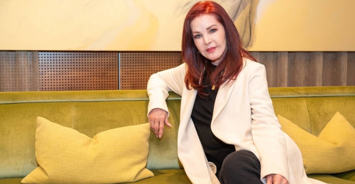 Priscilla Presley in Wien mit einem weißen Mantel und roten langen Haaren.