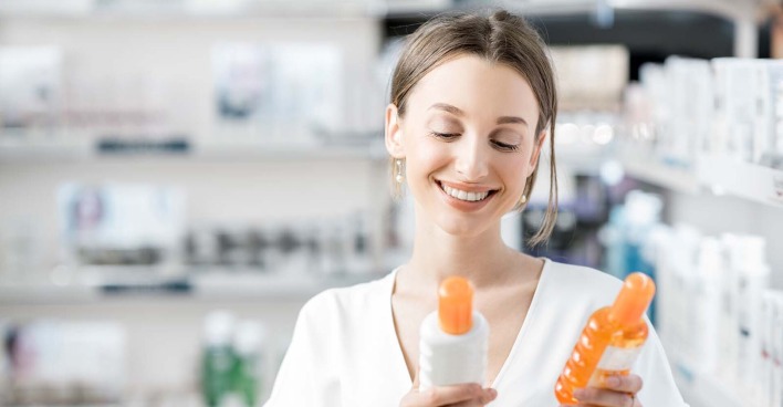 Frau mit Sonnencreme-Flaschen in der Hand | Credit: iStock.com/RossHelen