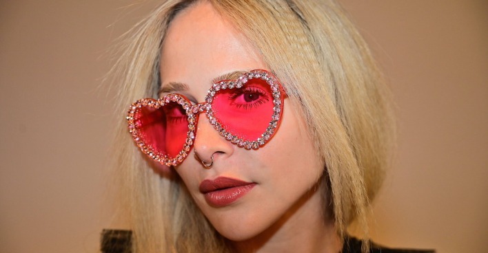 Model Theresia Fischer mit blonden offenen Haaren und einer rosa Herz-Brille.