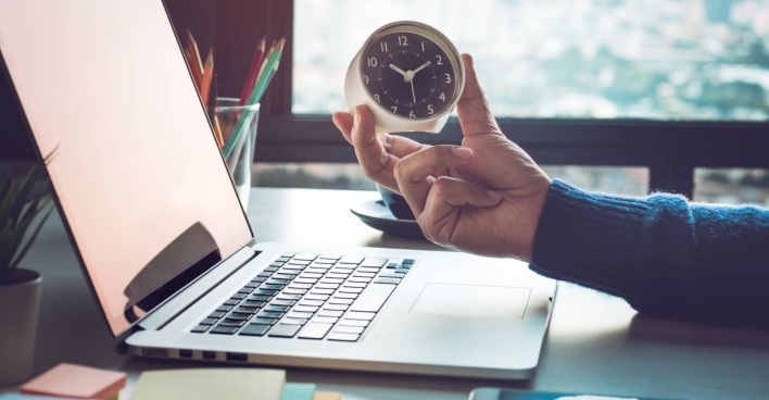 Schreibtisch mit Laptop, Uhr und Stifteköcher