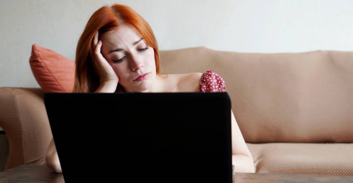 Frustrierte Frau vor ihrem aufgeklappten Laptop
