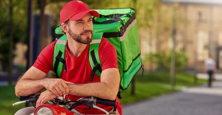 Essenslieferant am Roller mit rotem T-Shirt und roter Kappe