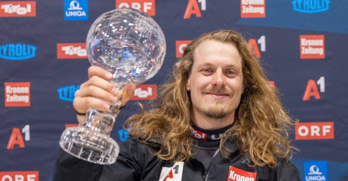 Manuel Feller mit wallender Mähne und seine Weltcup-Kugel bei einem offiziellen Fototermin