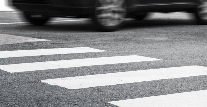 Eine Auto braust auf einem Zebrastreifen davon.