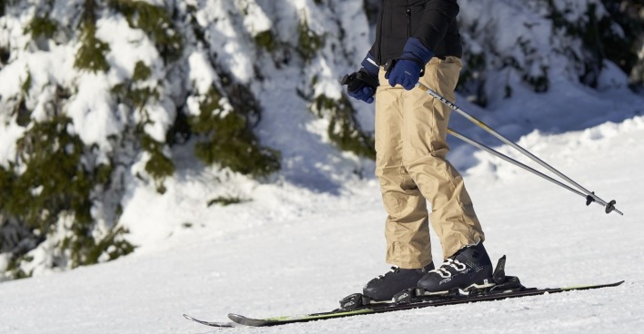 Ein Skifahrer mit Stöcken und beiger Skihose.