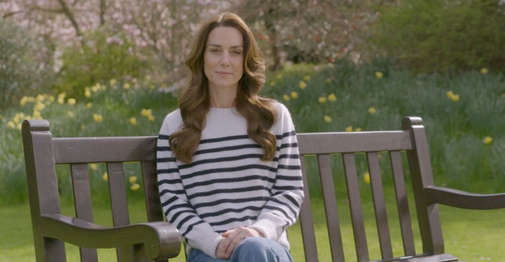 Prinzessin Kate sitzt auf einer Bank im Garten.