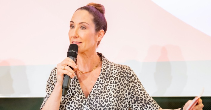 Kathi Bellowitsch mit einem Mikrofon auf einem Podium.