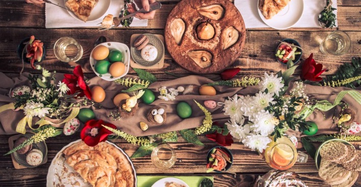 Bunt gedeckter Ostertisch mit traditionellen Speisen, gekochten Eiern und Tischdekoration in Erdtönen