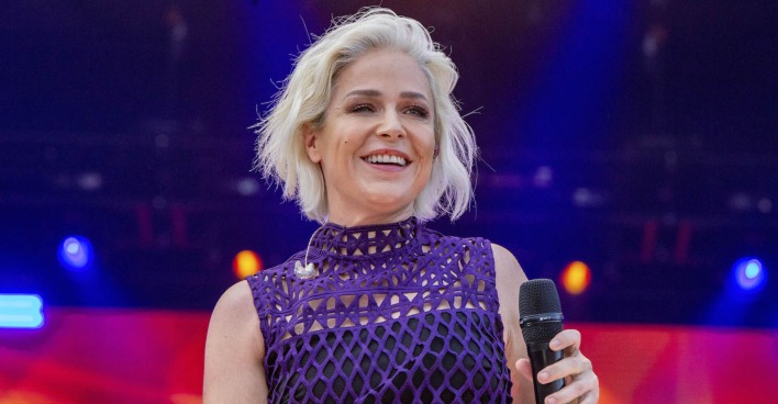 Schlagerstar Michelle mit einem violetten Oberteil und einem Mikrofon auf der Bühne.