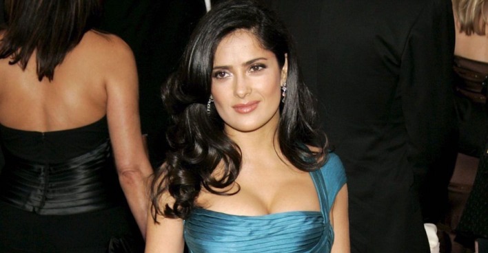 Salma Hayek mit einem blauen Ballkleid am Red Carpet und offenen braunen Haaren.