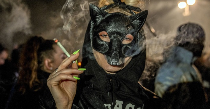 Frau mit Katzenmaske und Joint in der Hand