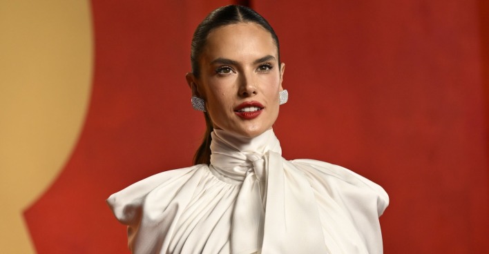 Alessandra Ambrosio mit einem weißen Oberteil und zurück gegelten Haaren auf dem Red Carpet.