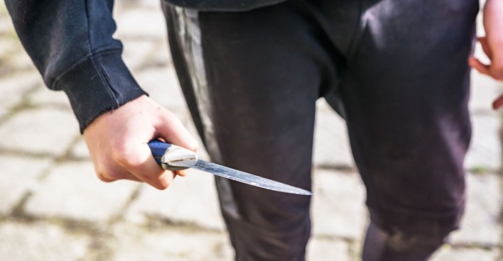 Ein junger Mann mit einem Messer auf der Straße.