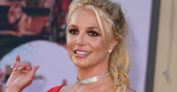 Britney Spears mit geschlossenen blonden Haaren und einer glitzer Kette.