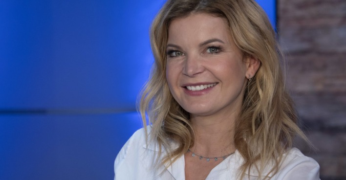 Eva Imhof mit einer weißen Bluse und gewellten blonden Haaren.