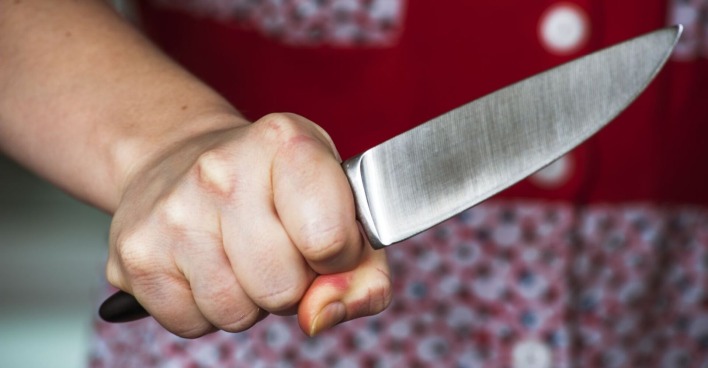 Eine Frau hält ein Küchenmesser bedrohlich in der Hand.
