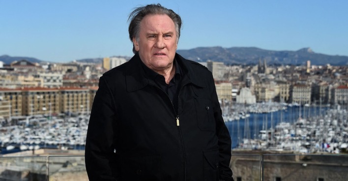 Gerard Depardieu auf einer Aussichtsplattform mit einem schwarzen Mantel.