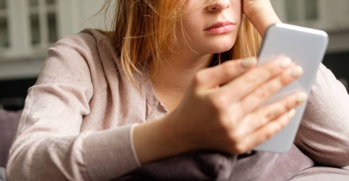 Frustrierte junge Frau mit einem Smartphone in der Hand