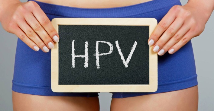Junge Frau die in der Höhe ihrer Hüfte eine beschriebene Tafel mit der Abkürzung 'HPV' hält