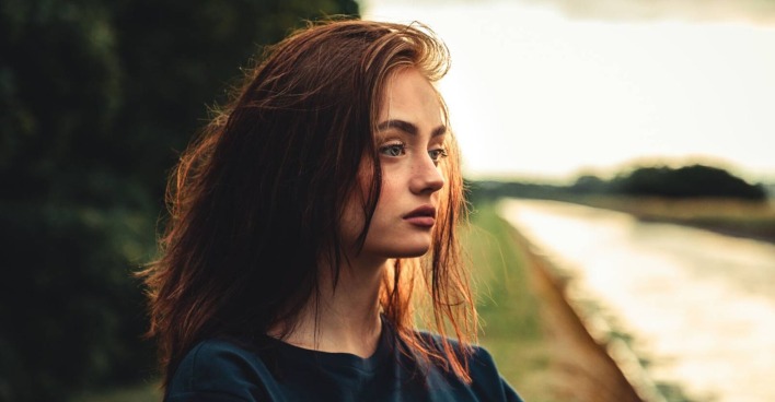 Nahaufnahme des Gesichts einer jungen Frau mit in die Ferne gerichtetem Blick