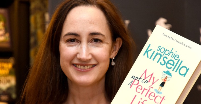 Eine lächelnde Frau hält ein Buch in die Kamera