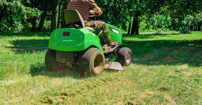 Ein Mann sitzt auf einem Rasenmäher-Traktor