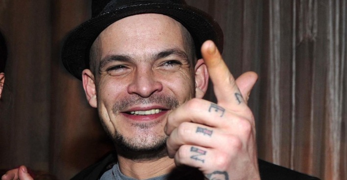 Ben Tewaag mit Tattoos auf den Händen und einem Hut.