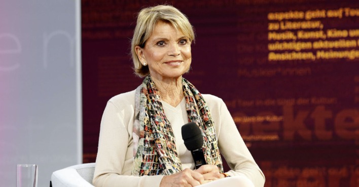 Uschi Glas mit einem beigen Outfit und einem Schal.