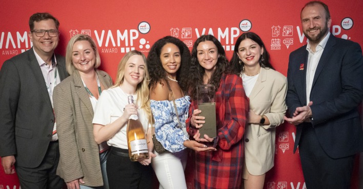 Platin-Award-Preisträger mit der Trophäe vor einer roten Wand