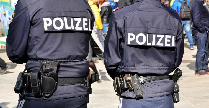 Zwei Polizisten, die mit dem Rücken zur Kamera stehen.