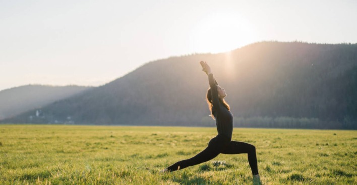 Eine Frau macht Yoga auf einer Wiese.