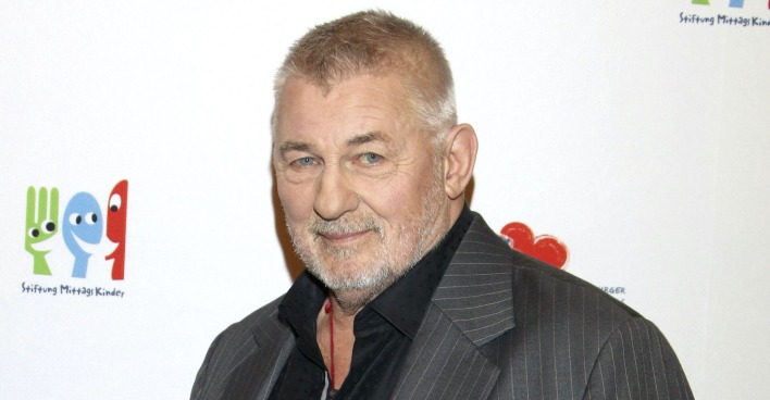 Heinz Hoenig mit einem grauen Anzug und einem schwarzen Hemd bei einem Event.
