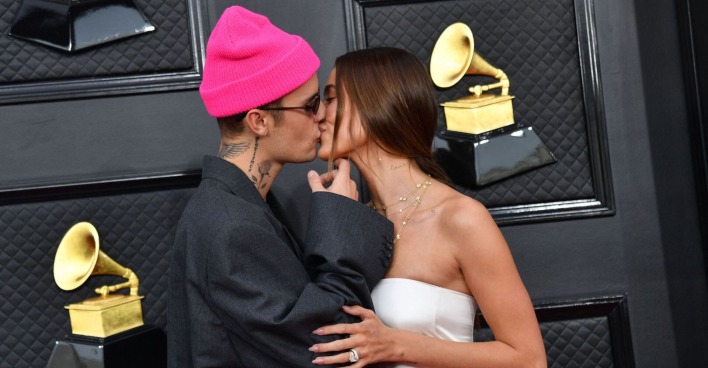 Justin Bieber trägt eine pinke Mütze und küsst seine Frau Hailey auf dem Red Carpet.