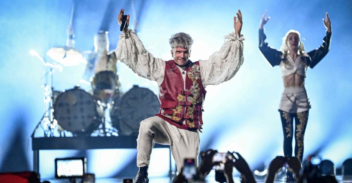 Ein Mann in mittelalterlichem Outfit steht auf der Bühne und hebt die Hände nach oben