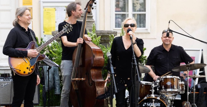 Vierköpfige Band mit Sängerin am Mikrofon, einem Chello-Spieler, einem Gitarristen und einem Schlagzeuger.