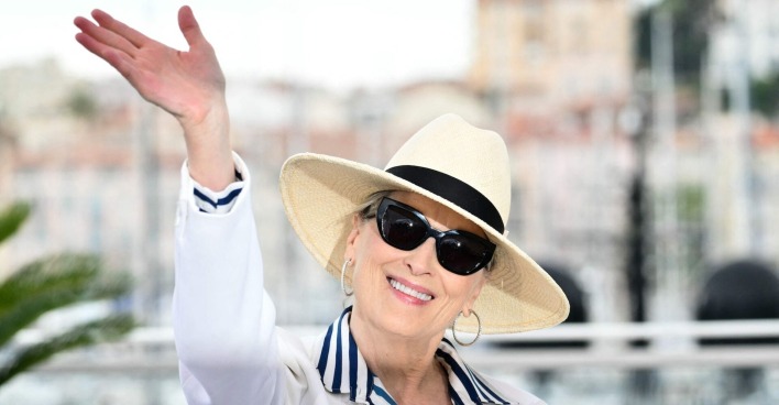 Maryl Streep in Cannes mit einem weißen Blazer, einem gestreiften Hemd, einer Sonnenbrille und einem Sonnenhut.