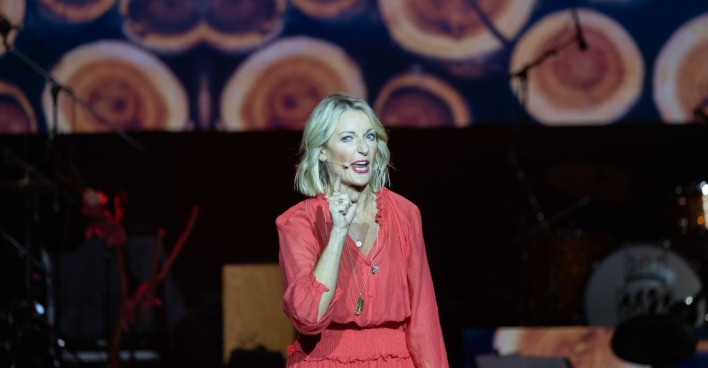 Monika Gruber in einem roten Kleid auf der Bühne.