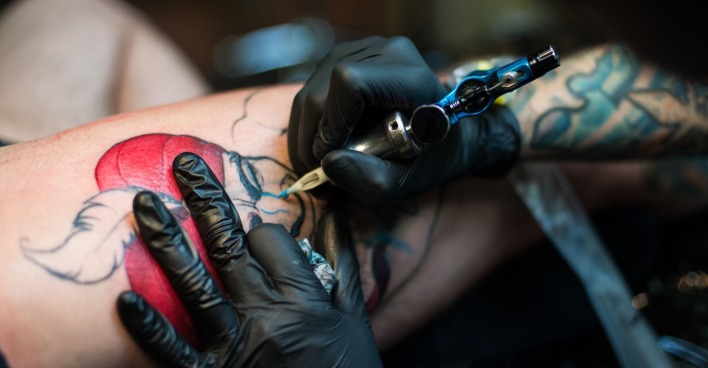 Ein Tätowierer sticht ein Tattoo.