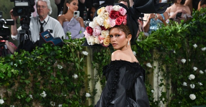 Frau in schwarzem Kleid mit großem Blumen-Hut
