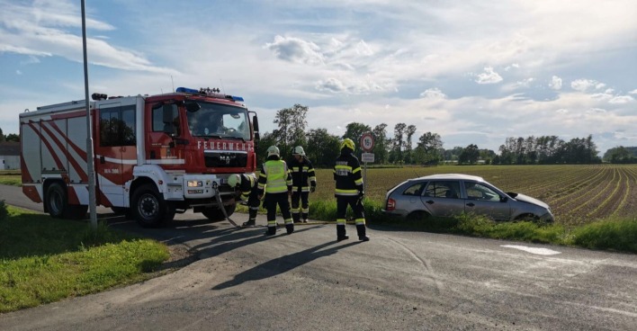 Ein Feuerwehrauto, Einsatzkräfte und ein Pkw im Straßengraben