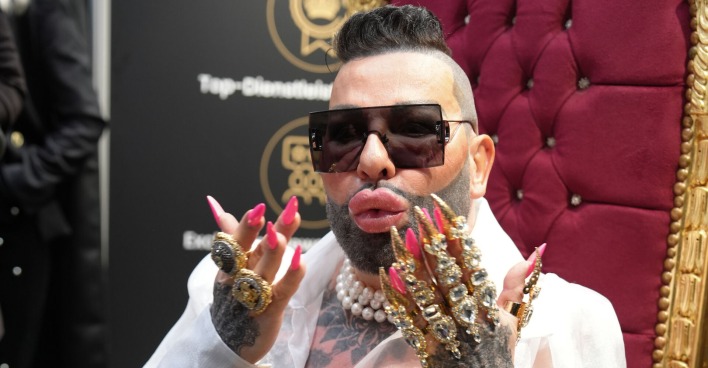 Harald Glöckler mit beschmückten Händen und pinken langen Fingernägeln. Er trägt kurze Haare und eine Sonnenbrille.