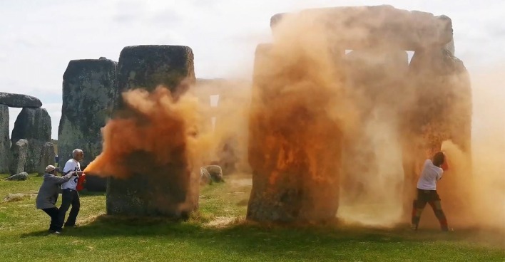 Zwei Klimaaktivisten besprühen Stonehenge mit oranger Farbe.