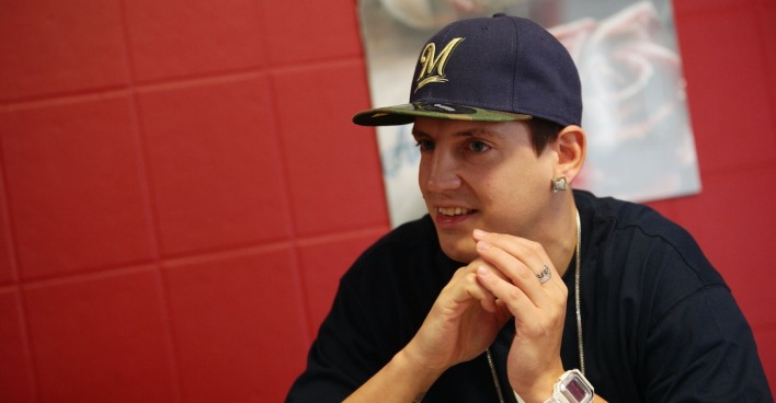 Money Boy mit einer schwarzen Kappe und einem schwarzen T-shirt vor einem roten Hintergrund.