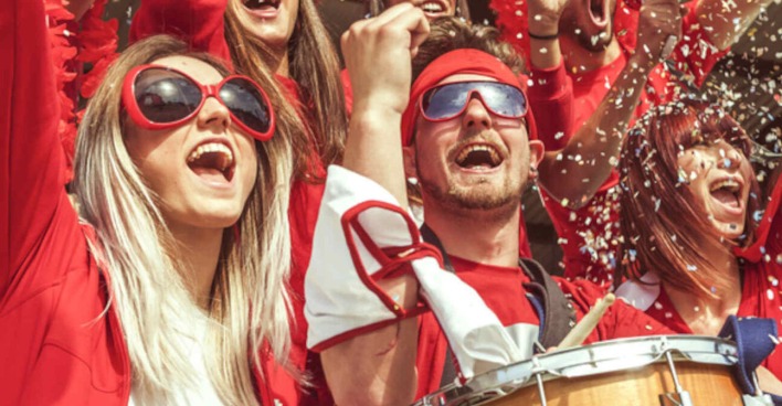 Mehrere Fußballfans sind in Rot gekleidet und jubeln