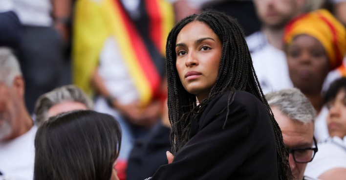 Eine Frau mit dunklen Haaren steht auf einer Tribüne im Stadion