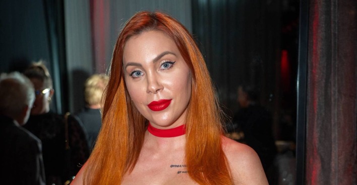 Tara Tabitha mit kupfernen langen glatten Haaren und einem knallroten Lippenstift.