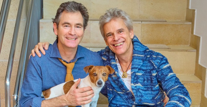 Thomas Brezina und sein Ehemann Ivo Belajic und Hund Joppy in einem blauen Hemd.