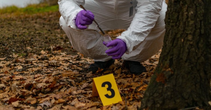 Ein Ermittler an einem Tatort in einem Wald.