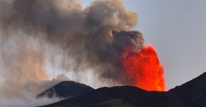 Lava schießt aus dem Krater des Ätnas in die Luft. Eine dicke Rauchsäule steigt auf.